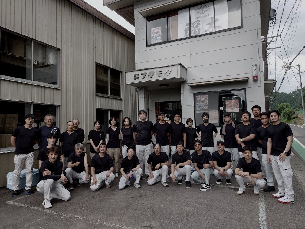 揃いの作業着で並ぶフクモクの職人たちの集合写真